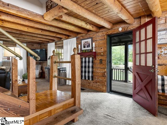 doorway with beam ceiling, carpet floors, and wood ceiling