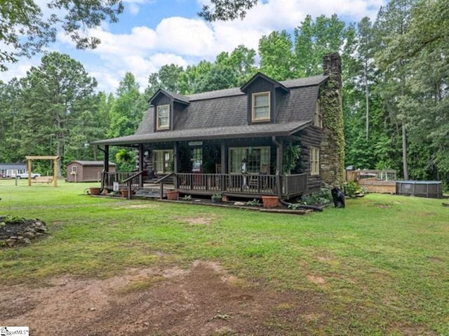 view of front of property featuring a storage unit, a porch, and a front yard