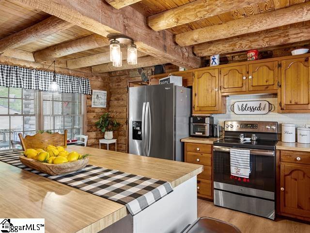 kitchen featuring pendant lighting, light hardwood / wood-style floors, stainless steel appliances, and beamed ceiling