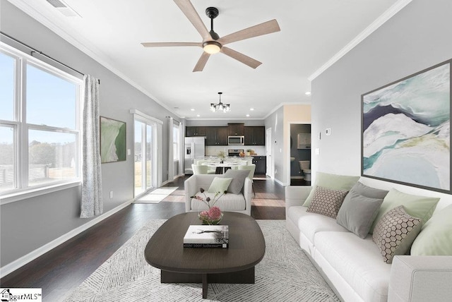 living room featuring dark hardwood / wood-style flooring, ceiling fan with notable chandelier, a wealth of natural light, and ornamental molding