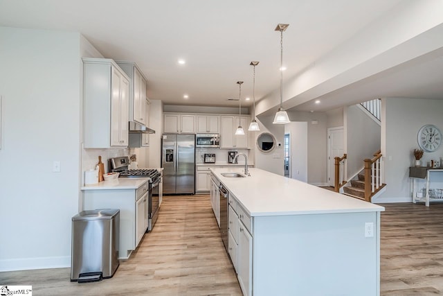 kitchen featuring pendant lighting, an island with sink, sink, white cabinets, and stainless steel appliances