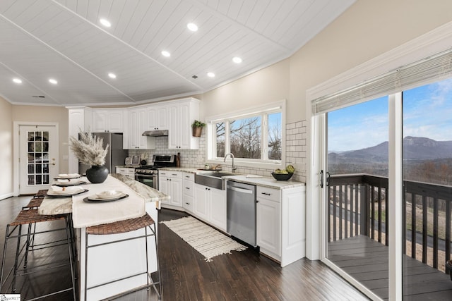 kitchen featuring a mountain view, a center island, sink, appliances with stainless steel finishes, and white cabinetry