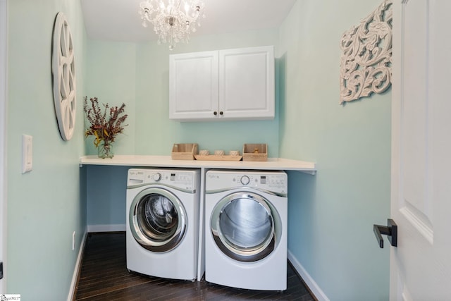 washroom featuring dark hardwood / wood-style floors, an inviting chandelier, cabinets, and washing machine and clothes dryer