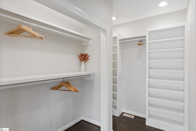 walk in closet with dark wood-type flooring