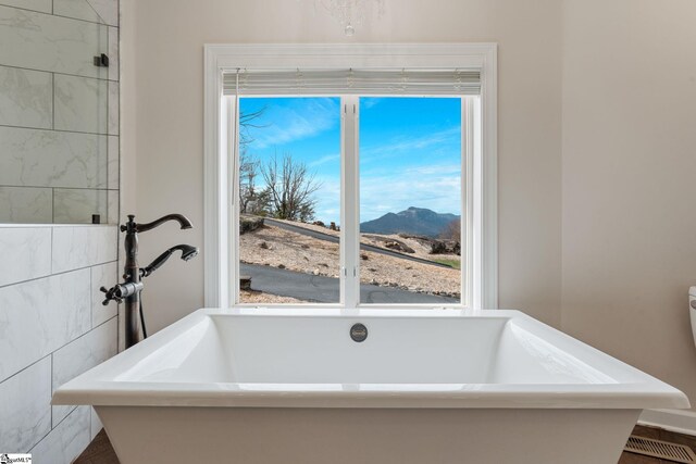 bathroom featuring a mountain view, a bathtub, and plenty of natural light