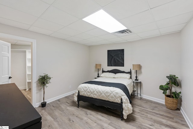 bedroom with a paneled ceiling and light hardwood / wood-style floors