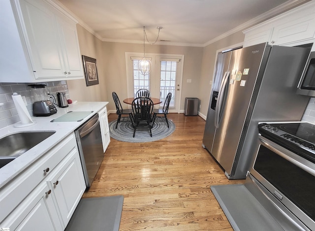 kitchen featuring backsplash, light wood-type flooring, appliances with stainless steel finishes, white cabinetry, and a chandelier