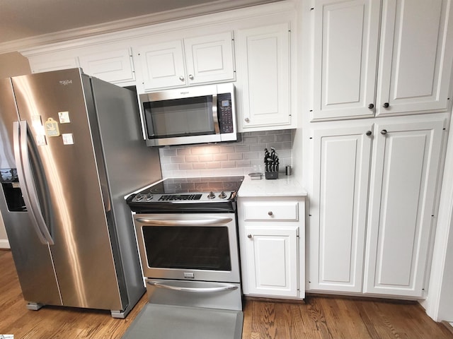 kitchen with white cabinetry, dark hardwood / wood-style floors, backsplash, appliances with stainless steel finishes, and ornamental molding