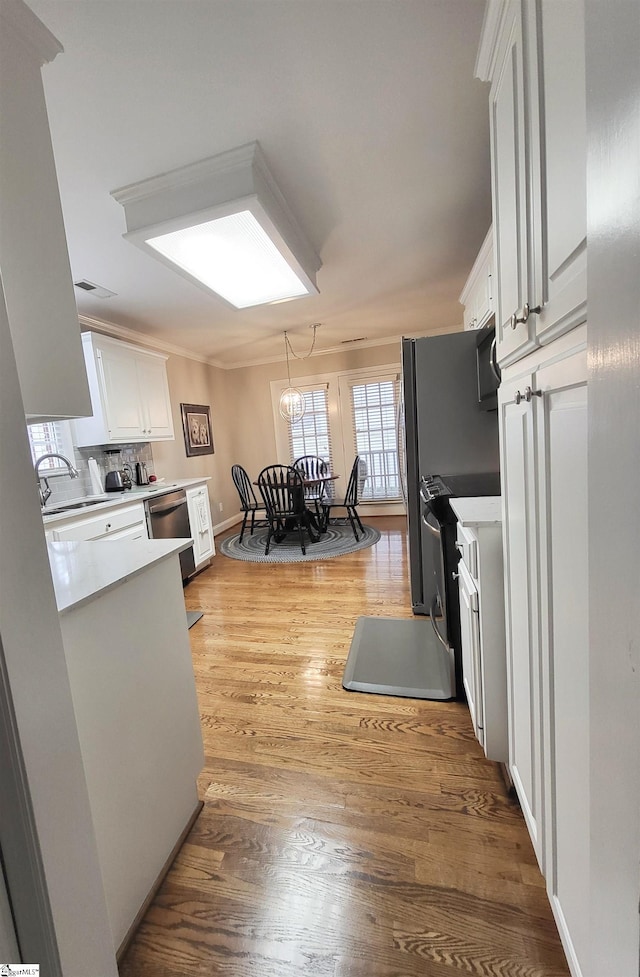 kitchen featuring sink, stainless steel appliances, a chandelier, light hardwood / wood-style floors, and white cabinets