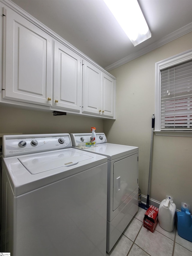 laundry room featuring washing machine and clothes dryer, light tile patterned floors, cabinets, and ornamental molding