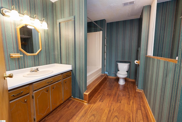 bathroom with wood-type flooring, vanity, a textured ceiling, and toilet