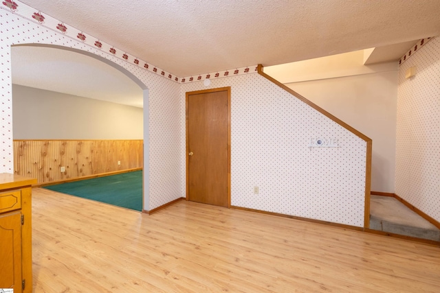 bonus room with hardwood / wood-style flooring, wood walls, and a textured ceiling