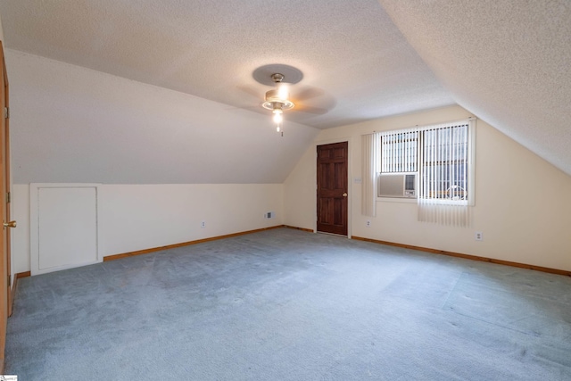 additional living space featuring carpet, a textured ceiling, vaulted ceiling, and ceiling fan