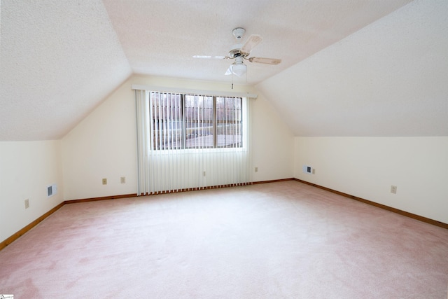 bonus room with vaulted ceiling, light carpet, and a textured ceiling