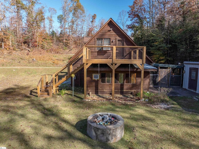 back of house with a fire pit, a yard, and a wooden deck