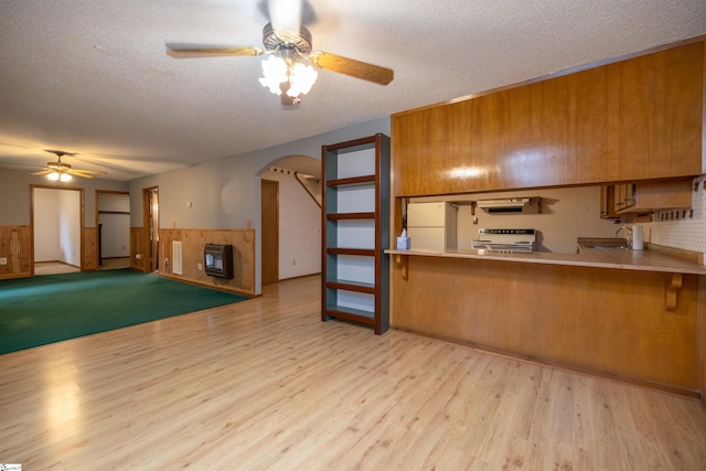 kitchen with decorative backsplash, stainless steel range oven, light wood-type flooring, and a textured ceiling