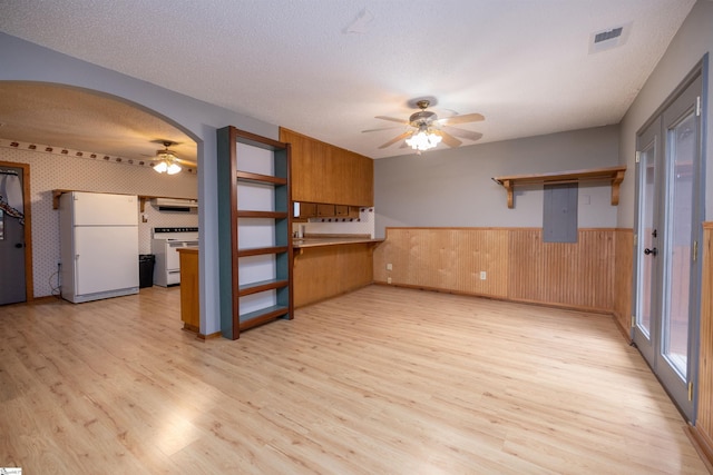 unfurnished living room featuring light hardwood / wood-style floors, a textured ceiling, ceiling fan, electric panel, and wood walls