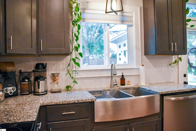 kitchen with light stone countertops, dark brown cabinets, and stainless steel dishwasher