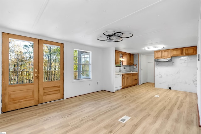 kitchen with french doors, tasteful backsplash, white dishwasher, sink, and light hardwood / wood-style floors