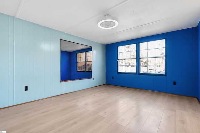 spare room featuring wood walls and light hardwood / wood-style floors