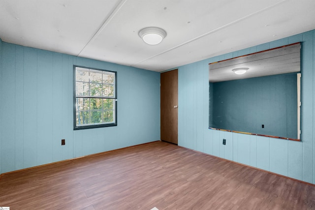 spare room with wood-type flooring and wooden walls