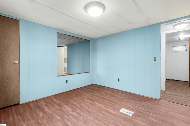 empty room featuring hardwood / wood-style flooring and wooden walls