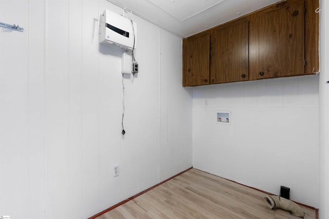 washroom featuring cabinets, hookup for a washing machine, light hardwood / wood-style floors, and wood walls