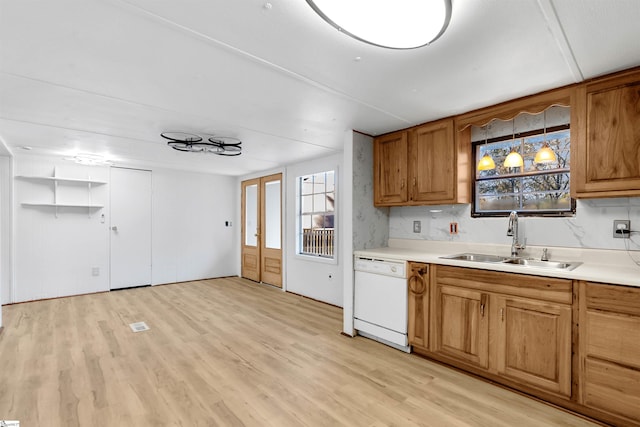 kitchen featuring decorative backsplash, sink, light hardwood / wood-style flooring, dishwasher, and hanging light fixtures