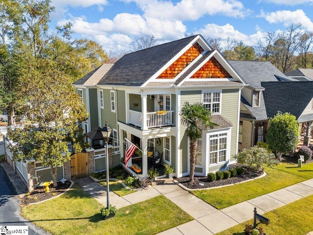 view of front of home with a balcony and a front yard