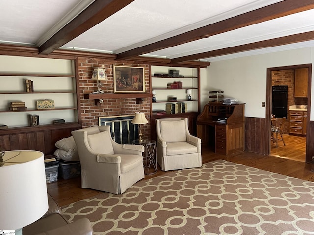 living room featuring hardwood / wood-style flooring, crown molding, beamed ceiling, and a brick fireplace