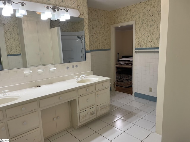 bathroom with a shower, tile patterned flooring, vanity, and tile walls