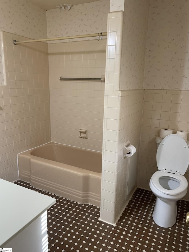 full bathroom with vanity, tiled shower / bath, tile walls, and toilet