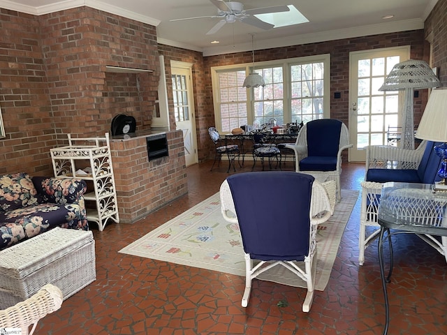 living room with a skylight, ceiling fan, brick wall, and ornamental molding