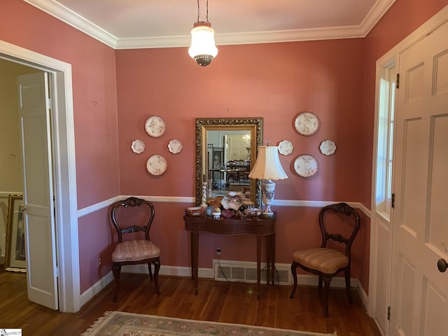 sitting room with ornamental molding and dark wood-type flooring