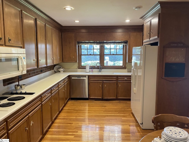 kitchen with light wood-type flooring, white appliances, and sink