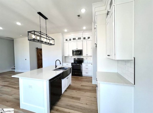 kitchen featuring black appliances, white cabinetry, sink, and light hardwood / wood-style flooring