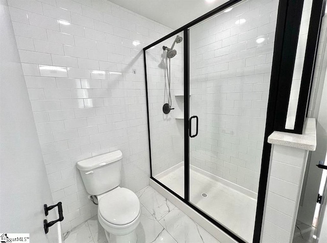 bathroom featuring a shower with shower door and toilet