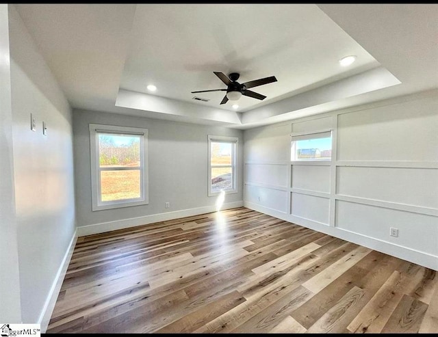 empty room featuring hardwood / wood-style flooring, a raised ceiling, and plenty of natural light