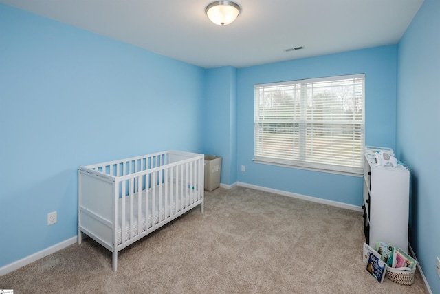 bedroom featuring light carpet and a nursery area