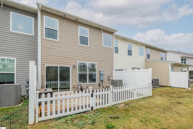 rear view of house with central AC and a yard