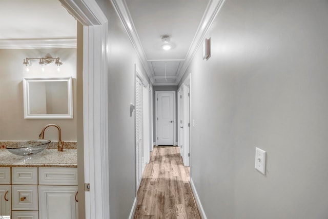 corridor with crown molding, sink, and light hardwood / wood-style flooring