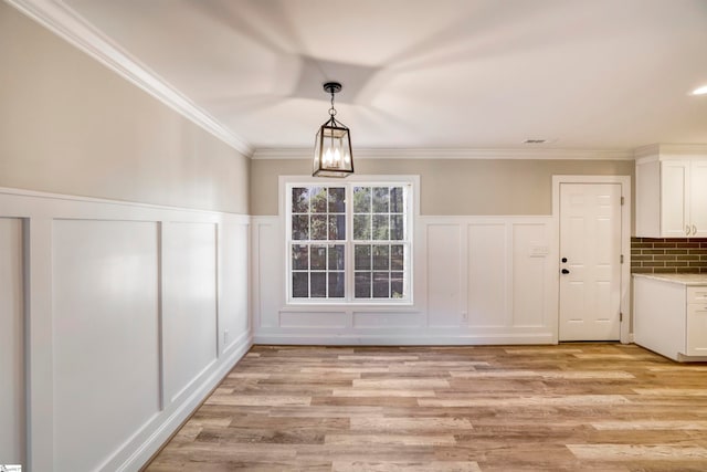 unfurnished dining area with a chandelier, light hardwood / wood-style flooring, and ornamental molding