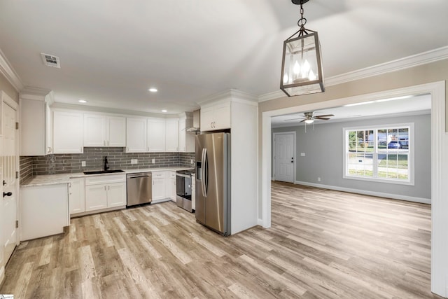 kitchen with white cabinets, pendant lighting, stainless steel appliances, and light hardwood / wood-style floors