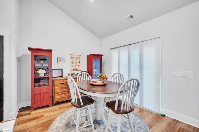 dining room featuring light hardwood / wood-style flooring and high vaulted ceiling