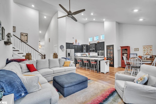 living room with ceiling fan, high vaulted ceiling, and light hardwood / wood-style floors