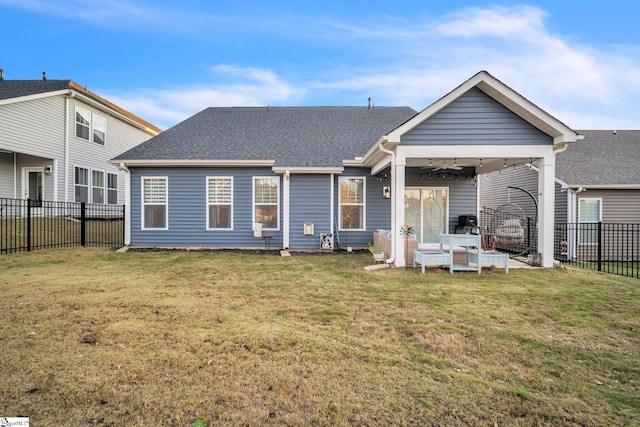 back of house with ceiling fan and a yard