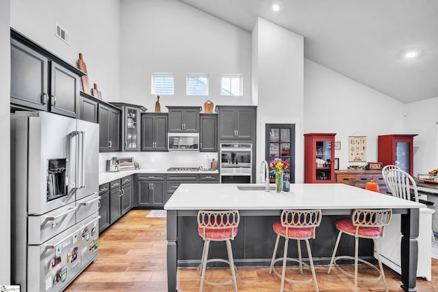 kitchen featuring a kitchen bar, a kitchen island with sink, and appliances with stainless steel finishes