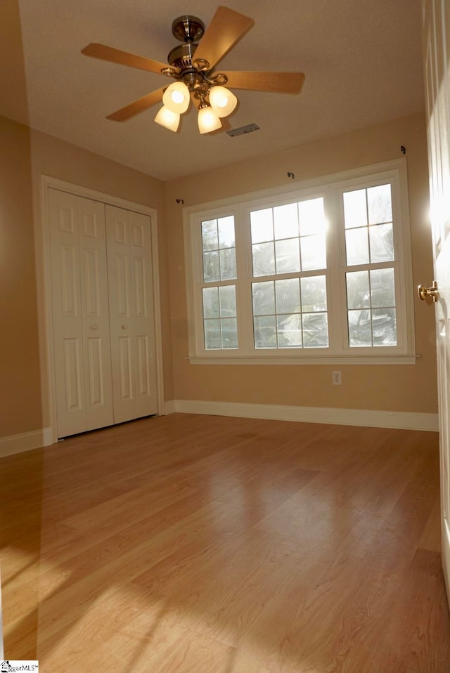 unfurnished bedroom with light hardwood / wood-style flooring, a closet, and ceiling fan