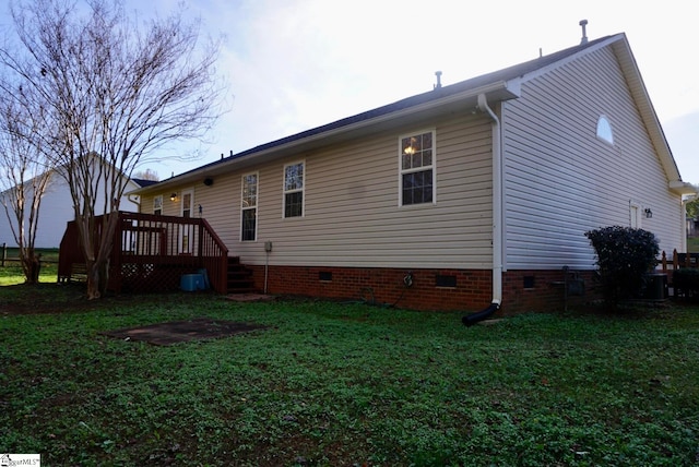 back of house featuring a lawn and a wooden deck