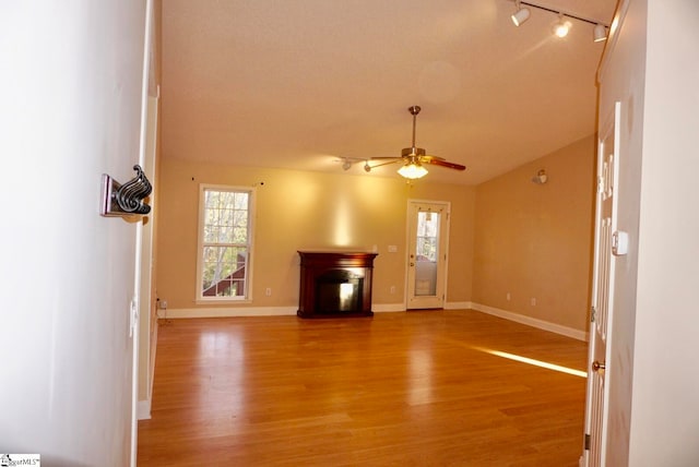 unfurnished living room featuring ceiling fan, a fireplace, wood-type flooring, and track lighting